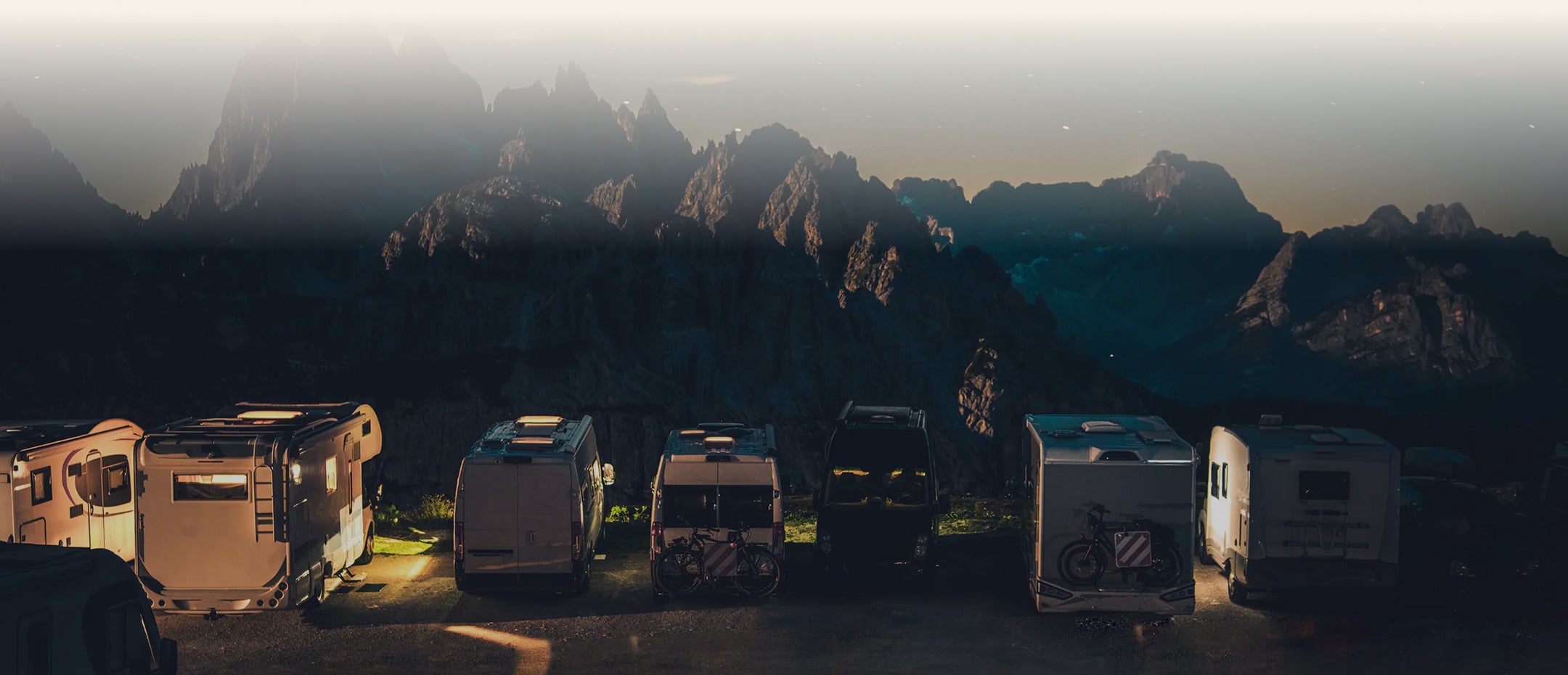 Row of RVs parked in a mountainous area at dusk